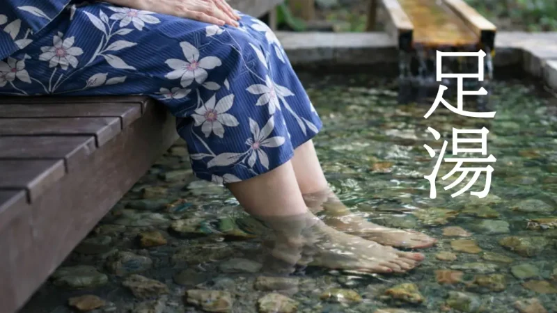 温泉街の足湯で温まりながらくつろぐ女性の様子